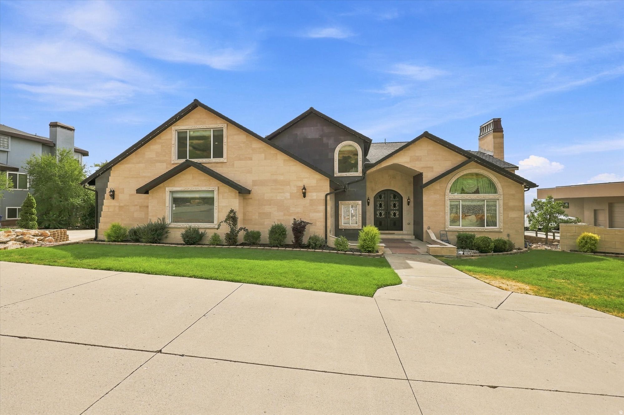 Stone exterior with dark trim accents, arched windows, and a prominent double entry door