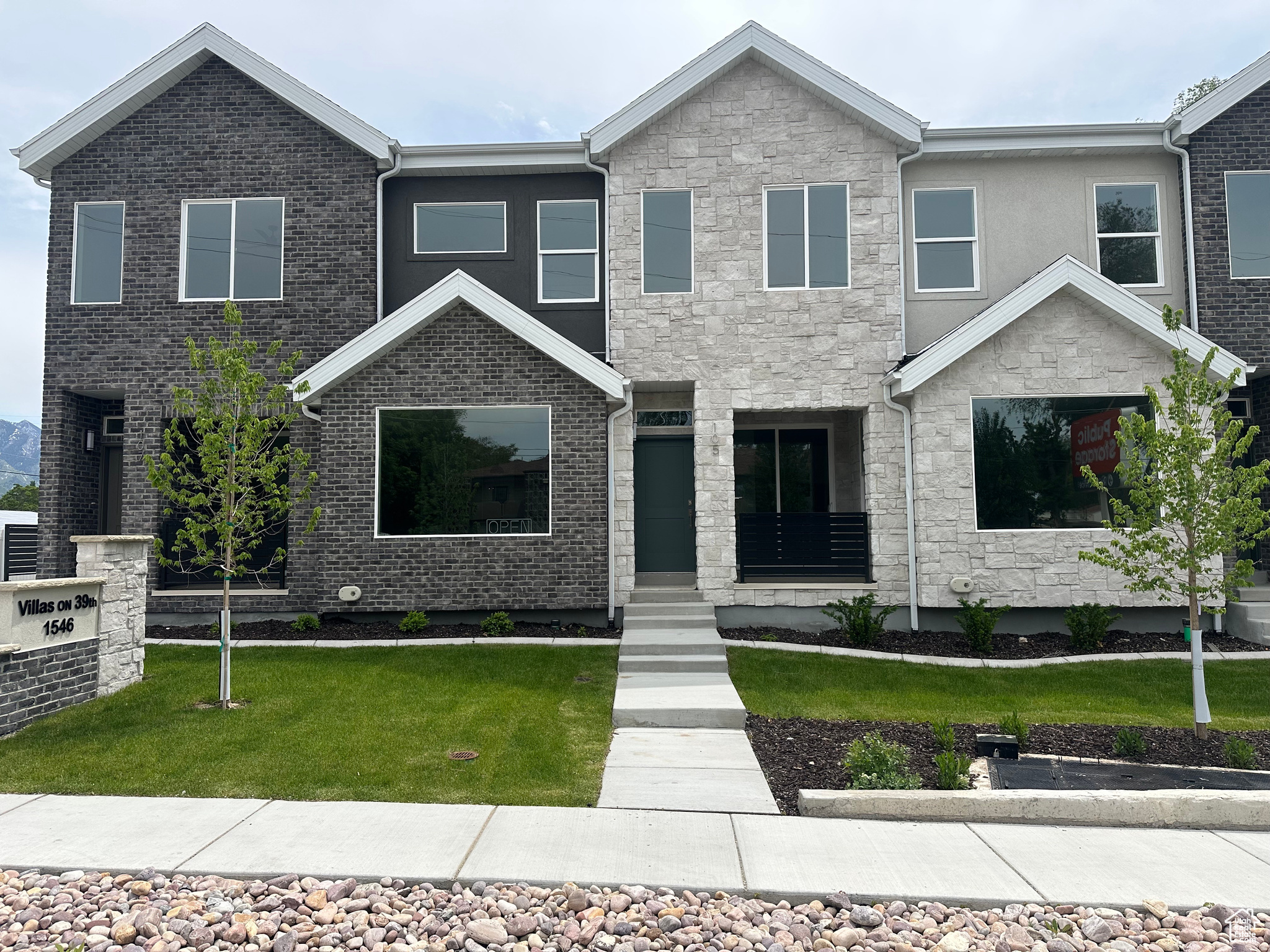 Modern townhome facade featuring a striking combination of dark brick and light stone veneer