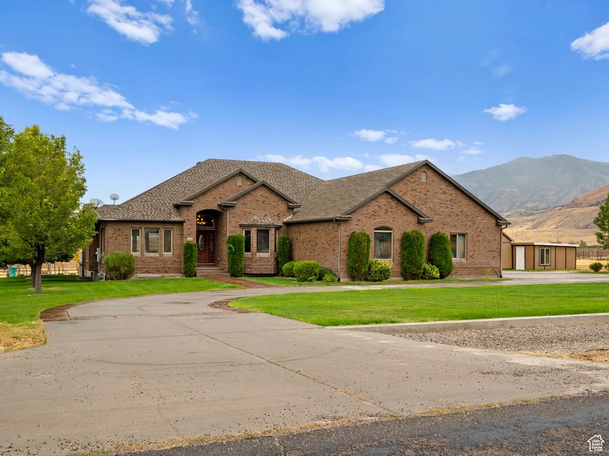 Discover refined living with lake views in this exceptional residence offering over 5,000 sq. ft. of space, nestled on 4.7 acres of beautifully landscaped grounds. From the moment you enter, the craftsmanship is undeniable-from 2x6 construction to custom cherry wood floors and intricate inlaid tile set the tone for timeless elegance throughout.  The oversized great room features vaulted ceilings, wiring for surround sound and provides ample space for entertainment of family and friends.  The kitchen boasts granite countertops, rich cherry cabinetry, and plenty of space for both entertaining and everyday living.  In addition to the bedrooms downstairs you will find two rooms that may be used as hobby, workout, theatre rooms or any other desired function.  Step outside to the stamped concrete patio and expansive covered deck, perfect for gatherings or simply taking in the serene surroundings. The patio has already been wired for a future hot tub location off the primary suite. The finished insulated six car garage with stained concrete floors adds both function and style while there is plenty of concrete pad outdoors for RV and toy parking.  The lower level impresses with a spacious kitchenette and wet bar-ideal for hosting as well as a family room wired for surround sound.  Outdoors, you'll find a true haven with mature landscaping and a remarkable collection of 20 fruit trees, several almond trees and grape vines blending beauty with productivity. This property also features two large garden areas.  There is a chicken coop by the orchard, shed and small animal kennel to the East of the house, and a horse shelter in the North pasture.  The property is fully fenced and cross fenced for grazing rotations.  Footings have already been poured for a future 60 x 60 foot barn, making this property perfect for those seeking space for animals, hobbies, or additional storage. Water right 15-4469 with 2 acre feet of water is included in the sale.   Square footage figures are provided as a courtesy estimate only and were obtained from county records.  Buyer is advised to obtain an independent measurement.