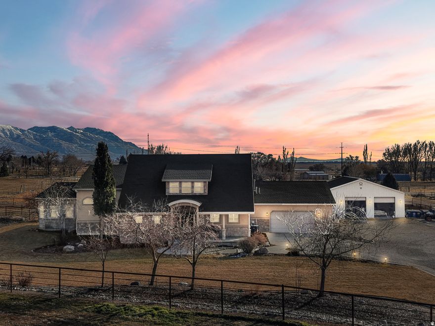 A recent investment has transformed this exceptional equestrian estate. Don't miss out on this stunning 6-bed home with 6,000+ sq ft on 5 acres, bring your horses! Features LVP floors, upgraded kitchen, radiant heat, luxe primary w/ porch & views. Finished walkout basement w/ fireplace, theater wiring & patio. Heated garages, sprinklers, equestrian setup w/ barn, arena & pastures. Inside, you'll find waterproof LVP flooring throughout, an upgraded kitchen featuring stainless steel appliances, granite countertops, and radiant heat with three zones. Just off the kitchen is a versatile space ideal for a butler's pantry or craft room. The spacious primary suite includes access to a charming covered porch with breathtaking mountain views, while the primary bath boasts an impressive custom walk-in closet. The fully finished walkout basement offers 9-foot ceilings, a large family room with a cozy gas fireplace that is prewired for speakers and a projector, making it ideal for a home theater setup. This level also includes a music-themed room, a dedicated space perfect for a home gym, and a large full bathroom. The basement opens to a covered patio, perfect for outdoor enjoyment. The attached 2-car main garage is gas-heated with its own thermostat, with an additional rear garage providing extra storage. Recent upgrades include a newer water softener, instantaneous hot water, and a sump system. A smaller garage with 220V power is ideal for lawn equipment or recreational toys. The landscaped yard features a 22-zone sprinkler system. The home's acre is on culinary water, with the remaining 4 acres on irrigation water. Enjoy mature fruit trees, including peach, plum, apricot, and almond. Equestrian amenities include an over 1,800 sq ft detached barn with four horse stalls and outdoor runs, a 60' round pen, a 190' x 160' arena, three pipe-fenced horse pastures with shelter, and another larger pipe-fenced horse pasture offering room for future development.