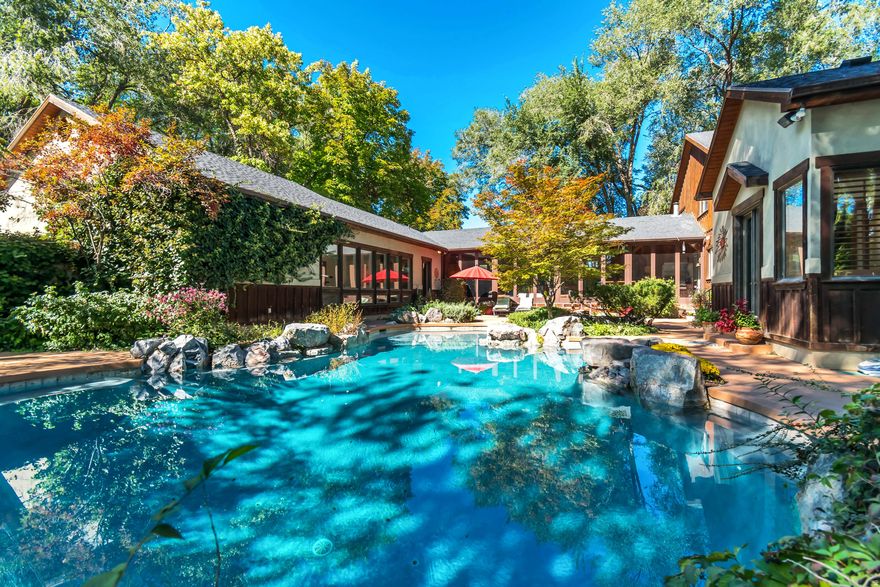 Tucked away on 3.10 secluded acres, this remarkable property offers both privacy and luxury. A mature tree-lined driveway leads to a beautifully landscaped oasis featuring a courtyard-style backyard, custom pool with spa-like ambiance, and an in-ground hot tub and waterfall. Inside, vaulted ceilings and a thoughtfully designed floor plan create an inviting atmosphere. The gourmet kitchen is complemented by a screened-in patio with an outdoor grill and wet bar perfect for entertaining. The main-floor master retreat offers direct access to the pool and spa, creating the ultimate private escape. Additional amenities include a large home gym, outdoor fireplace and patio, firepit, horseshoe and shuffleboard areas, basketball standard, and expansive parking for all your toys and equipment. A detached oversized garage and workshop, is fully equipped with everything you could need including 220v power, a dust collection system, office and half bath. In addition to the workshop you'll find a 3-bedroom, 2-bathroom, accessory apartment providing the perfect guest retreat or potential rental income. Reach out today to make this property with endless opportunity, your own. Buyer/Buyer's Agent to verify all info.