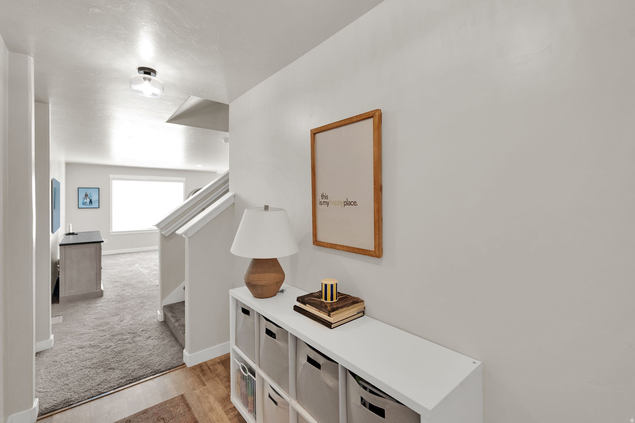 Entryway with hard-surface flooring transitioning to carpet, featuring a staircase with white risers and handrails, and a flush-mount ceiling light fixture