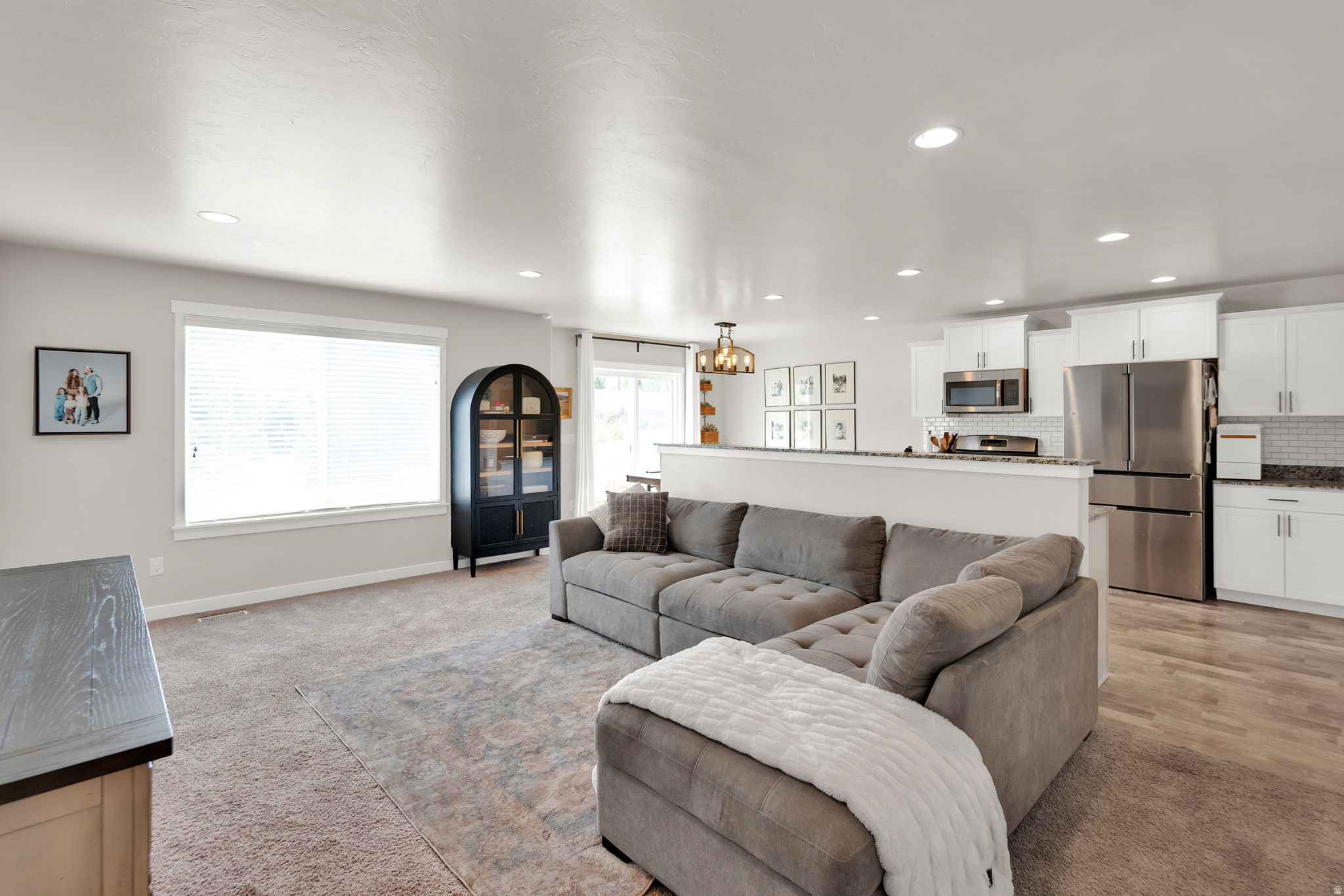 Open-concept living area featuring recessed lighting, a large window with blinds, and light-toned walls