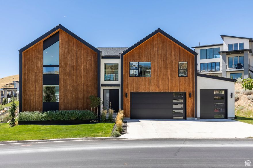 Modern Scandinavian Elegance on Traverse Mountain! Perched atop the prestigious Vialetto community, this Scandinavian Modern masterpiece redefines luxury living with breathtaking views of Silicon Slopes and Utah Lake. Every detail of this custom- designed residence reflects unparalleled craftsmanship and cutting-edge style. Step into the awe-inspiring great room, where 25-foot ceilings, exposed steel beams, and ambient LED lighting create a striking first impression. A floating staircase serves as a centerpiece, seamlessly connecting the open-concept living spaces. The gourmet kitchen is both functional and stunning, boasting commercial-grade appliances, Quartzite countertops, and a hidden Butler's pantry - perfect for effortless entertaining. The two-story family room, anchored by a Venetian plaster fireplace and rich wood flooring, offers a panoramic backdrop of city lights and mountain vistas. The main level is home to a serene Owner's Retreat, complete with plush carpeting, an expansive walk-in closet, and an adjoining laundry room for ultimate convenience. The spa-like en suite bath features a custom walk-in shower with Brizo brass fixtures, bespoke cabinetry, and porcelain countertops designed for relaxation and indulgence. Upstairs, a lofted office and children's lounge overlook the lower level, enhancing the home's airy design. Two additional bedrooms, a stylish bathroom, and a spacious entertaining area with a walkout deck provide both comfort and stunning valley views. The newly finished basement takes entertainment to the next level with a sleek, moody aesthetic. A kitchenette equipped with a Fisher & Paykel double-drawer dishwasher, ambient lighting, and a custom backsplash complements a built-in entertainment center with a hidden door leading to extra storage. This level also includes two bedrooms and bathrooms, offering a private retreat for guests or family members. The home's exterior is equally impressive, with distinctive modern design, lush landscaping, and breathtaking views from every vantage point. Located moments from upscale shopping, fine dining, and convenient freeway access, this architectural gem combines the serenity of mountain living with the vibrancy of city life. Don't miss the opportunity to own this one-of-a-kind treasure on Traverse Mountain.