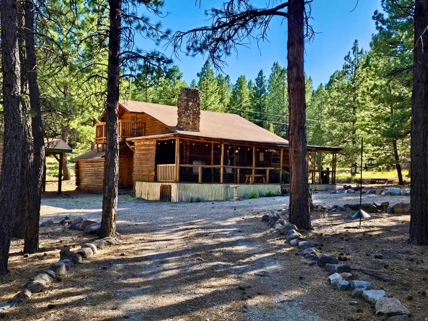 Escape the noise in this authentic log cabin nestled among the pines of the Yellow PineMammoth Creek community. Set on a rare level lot, this inviting retreat features real log construction, a wood-burning fireplace, vaulted ceilings, and warm living spaces that capture the essence of true mountain living. Recent improvements reflect thoughtful care and pride of ownership, including new double-pane windows installed in 2024, fresh exterior stain in 2024, and a new metal skirt added in 2025. The main level features a spacious primary bedroom and full bath, along with a new large-capacity AC window unit to keep things cool during warmer months. Upstairs, you'll find a second private bedroom, a loft space, and a second AC unit for added comfort. The loft opens to a second-story deck, an ideal spot to enjoy evening drinks, take in forest views, or watch wildlife wander through the property. The kitchen offers generous counter space and a dining bar for easy meals, while laundry is conveniently located on the main floor. Covered decking on the main level invites slow mornings with coffee, quiet afternoons, and relaxed evenings surrounded by nature. A detached 400-sf garage with double swing doors provides ample space for storage, tools, or outdoor gear. A new septic tank was installed in 2021. Offered furnished with nearly new furnishings, this cabin is turn-key and ready for immediate enjoyment. Seasonal summer water is supplied to the cabin from a community well, along with two additional water storage tanks totaling 825 gallons, helping extend your time in the mountains beyond the summer season. Walk to Mammoth Creek to fish or explore, enjoy miles of nearby national forest trails, or simply unplug and recharge on this quiet, private dead-end road surrounded by fresh mountain air. This is not a suburban home-it's a true mountain cabin, ideal for those seeking peace, quiet, and a genuine connection to nature.