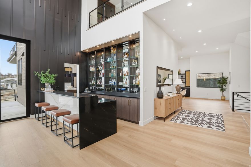 A rare masterpiece of modern design and sophistication, with nearly 7,000 sqft of seamless indoor-outdoor living with unobstructed panoramic views of the Wasatch Mountains and city skyline. Every detail of this architectural gem, perched on a premium lot in South Jordan, minutes from the freeway and walking distance to the Jordan River trail system, was crafted for both high-end entertaining and everyday luxury. This 6-bedroom, 7-bathroom home, is equipped with an elevator and premium finishes throughout. Step inside to soaring ceilings, expansive glass walls, and a light filled open floor plan that flows effortlessly from one curated space to the next. The home features multiple entertainment zones-including a a wet-bar adjacent to multiple decks off the front, 10' accordion great room glass doors that open up to a 600 sqft' covered patio off the back, a home gym, theatre room and and an oversized loft that overlooks the great room. The sleek entertainers kitchen with paneled Thermador appliances, Taj Mahal Quartz countertops and the secondary prep kitchen, anchors the main level living great room with sweeping vaulted ceilings, an impressive dining space and accompanying coffee bar. One of two Primary Suites is found on this main level. In the upper levels, find a 2nd Primary Suite with double sinks, euro glass shower, his and her wardrobes and a private balcony retreat. The secondary bedrooms all feature walk-in closets and ensuite bathrooms. Additionally, the home is equipped with a ground level iron door entry, a secondary bedroom and bath for multi-generational living, an elevator that takes you to levels 1 and 2 for step-less entry, a 3rd floor crows' nest office and private balcony retreat and a spacious 4-car garage, complete with ample parking, EV hookups and additional storage. The main level has space to create a theatre room, dance studio, additional garage space and / or a home gym. The landscaping will be completed with thoughtfully selected shrubs and trees, sod, automated water systems, and is ready to add your personal touch, with ample space for a pool, pickle-ball court and more. This home is the ultimate resident for upscale entertaining and unwinding in style.  Most furniture can be included in the Sale. Call Listing Agent for details.