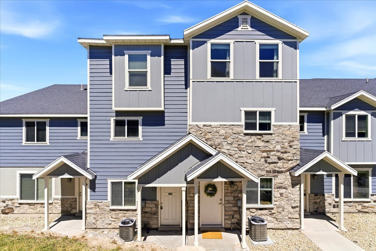 Multi-level exterior featuring blue horizontal siding, grey vertical siding, and natural stone veneer accents