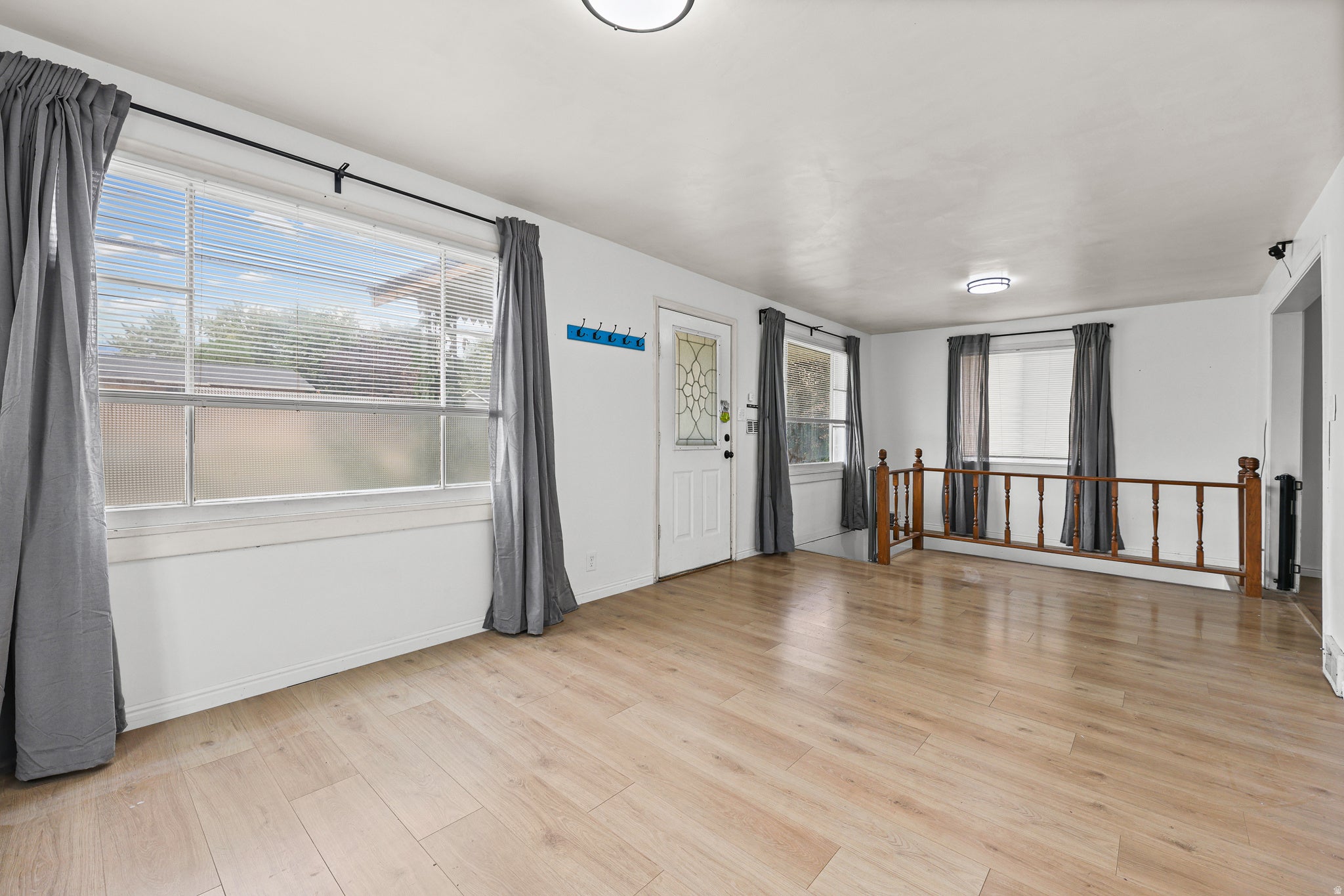 Living Room / Entry ? Bright, open living space featuring warm wood-look flooring, large windows, and abundant natural light. The room flows naturally toward the entry and adjoining areas, creating a comfortable gathering space.