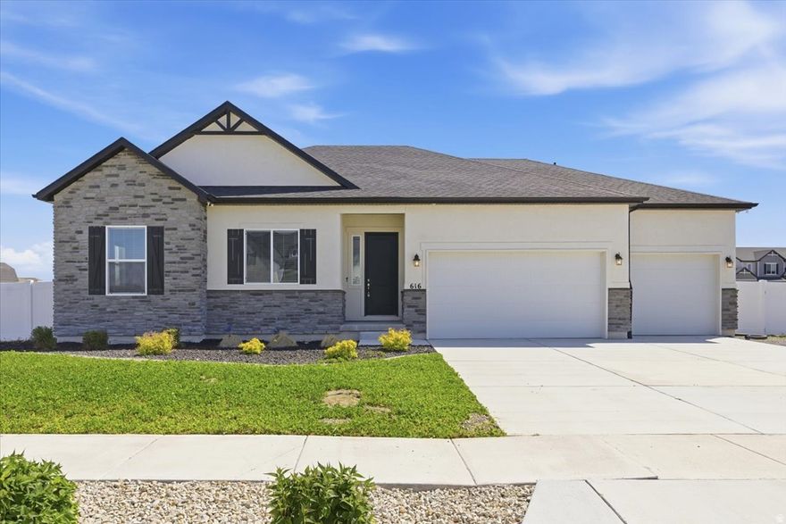 Welcome to this like-new 2022 rambler nestled on a half-acre lot in one of Grantsville's most peaceful neighborhoods, where beautiful views and quiet surroundings set the tone from the moment you arrive.  From the moment you step inside, the quality of this home is immediately apparent. The sellers spared no expense during the build, selecting upgrades throughout that elevate every room above standard new construction.  The great room is anchored by soaring tray ceilings, an abundance of natural light, and a stunning gas fireplace with a dark espresso surround and classic mantle, the perfect centerpiece for Utah winters. Rich dark LVP flooring flows seamlessly throughout the entire main level, tying together a cohesive and polished look that is as durable as it is beautiful.  The open floor plan connects the living room directly to the formal dining area and the kitchen, making this home ideal for both everyday living and entertaining. The kitchen is a true showpiece. Dark espresso shaker cabinets reach to the ceiling, providing exceptional storage, and are complemented by white quartz countertops and a full extended mosaic tile backsplash that runs the entire length of the wall. The large center island seats four comfortably and serves as the heart of the home. Appliances include a stainless steel built-in double wall oven, a separate induction cooktop, a wall-mounted stainless range hood, and a French door refrigerator. A generous walk-in pantry rounds out a kitchen that truly has it all.  One of the most clever upgrades in the home is a dedicated central vacuum inlet installed beneath a kitchen cabinet, allowing you to simply sweep debris directly into the wall without ever pulling out a hose. Small detail, big quality of life.  The open stair railing with dark wood spindles adds an architectural touch that opens up the sightlines between the main level and the basement below, giving the home a custom, elevated feel.  The oversized garage accommodates up to four vehicles and has been fully upgraded for the hobbyist or serious craftsman, with ten additional outlets installed for woodworking and workshop use, plus a 240V circuit ready for a welder, compressor, or future EV charger.  The owned solar panel system with backup battery transfers free and clear, and this is not your average solar setup. The panels keep the battery fully charged first, with any surplus energy sent back to the grid for a bill credit. When the grid goes down, the battery automatically keeps essential circuits running including the refrigerator, freezer, microwave, kitchen lights, and internet. The system is also configured so the grid cannot draw from your battery, meaning the power stays right where it belongs, in your home.  The front lawn features an intentional clover ground cover, a smart and increasingly popular alternative to traditional grass that is especially well suited for Utah's dry climate. Clover stays green with far less water than conventional turf, requires little to no mowing, and needs no fertilizer since it naturally fixes nitrogen in the soil. The backyard is partially landscaped and features a shade tree, three fruit trees, and raised garden boxes, with plenty of room to customize and grow on this spacious half-acre.  And then there is the basement. At a full 2,393 sq ft, this is not a typical unfinished space. It is a blank canvas of rare size with serious income potential. Comparable finished basement units in Grantsville are currently renting between $1,675 and $1,850 per month. Whether you are looking to offset your mortgage, create a long-term rental, or build out a mother-in-law suite, the numbers make a compelling case. We also have a trusted network of contractors available to help you finish the space to your specifications, making the path from potential to income as straightforward as possible.