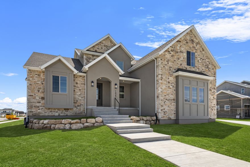 Thoughtfully designed for both style and livability, this brand new custom home in Lehi offers 5 bedrooms, 3.5 bathrooms, and refined finishes throughout. Situated on a generous 1/3 acre lot, the home provides space, natural light, and intentional design in a sought after neighborhood with no HOA. At the heart of the home is a beautifully appointed kitchen featuring tailored cabinetry, a statement range hood, a walk through pantry with dual entry, a Forno 8 burner gas range, and full size refrigerator and freezer. Two story living room ceilings and expansive windows fill the home with natural light. Step outside to the covered deck overlooking the spacious backyard, creating an ideal setting for both everyday living and entertaining. The main level primary suite offers an upscale private retreat with a freestanding soaking tub, oversized shower, and walk in closet. Upstairs includes four additional bedrooms, a playroom, two full bathrooms, and a second full laundry room, with a convenient Jack and Jill layout between two bedrooms. The walkout basement is designed for easy future completion and can be finished as an ADU. A three car garage provides ample parking and storage. Ideally located near shopping, dining, schools, and the Silicon Slopes corridor.