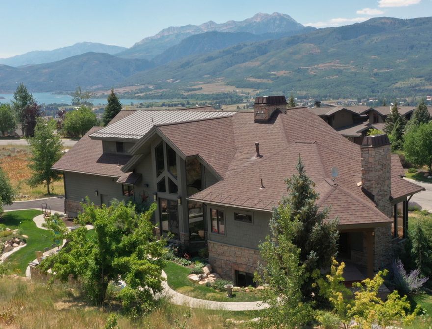 Experience breathtaking lake and mountain views from this custom-built 4,452 sq ft luxury retreat in The Highlands at Wolf Creek. Only a few residences in The Highlands can boast about the unparalleled views from every room in this custom residence build with superior craftmanship by Buxton Builders in 2007. Our stunning listing features soaring ceilings and arches, custom Pela windows throughout and every door is stunning custom Alder wood with solid wood trim and custom arches. Enjoy a Modern styled wrap-around covered deck for summer and winter enjoyment   Picture yourself savoring sunset views from the deck after a day boating on Pineview or unwinding by the outdoor fireplace and cookery after carving fresh powder at Snowbasin or Powder Mountain. Views of Snowbasin, Nordic Valley, Pineview, Ben Lomond Peak of the Wasatch Back, and the Ogden Valley.The open-concept living, dining, and gourmet kitchen is welcoming with its cathedral ceilings, a custom hand-blown glass chandelier, a dramatic floor-to-ceiling stone fireplace, custom Alder wood cabinetry, granite countertops, and Wolf appliances. The main-level primary suite features its own stone fireplace, spa-inspired bath with soaking tub, and a sauna. Upstairs, you'll find a second en-suite primary, plus a private study with custom floor-to-ceiling cabinetry. Luxury finishes include walnut floors, handmade 10-foot doors, and custom lighting throughout. The lower level offers two additional bedrooms, a large 3/4 bathroom, a theater room with velvet curtains and leather seating, new HD projector, Sonos surround sound, and a cozy fireplace-plus space for a pool table or game area.  The radiant heat flooring keeps it warm in the winter and even without air conditioning, the lower-level stays cool during the summer months. Enjoy year-round outdoor living on the expansive patio with built-in grill, stone fireplace, and private hot tub. A heated 3-car garage with storage, meticulously landscaped .88-acre lot, pre-listing inspection, and option to purchase two additional lots make this an exceptional mountain home.