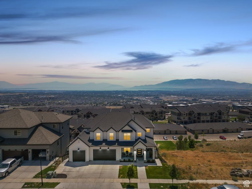 Farmhouse charm meets city life in this beautifully crafted home nestled in Traverse Mountain, right in the heart of Utah's Silicon Slopes. With breathtaking views of Utah Lake and the valley beyond, this inviting home blends timeless character with modern comfort. Step inside to an open-concept layout centered around a grand two-story fireplace-a perfect gathering spot on cozy evenings. The main-floor primary suite is a peaceful retreat with a spa-inspired bath featuring a freestanding soaking tub, oversized shower, dual vanities, and custom cabinetry for storage. The heart of the home opens to a farmhouse-style kitchen designed for both function and warmth, ideal for hosting family and friends. Downstairs, you'll find room for every kind of living-enjoy a gym, guest bedrooms, and a charming second full kitchen as part of a separate two-bedroom ADU. Whether for guests, extended family, this second kitchen adds versatility and value. Outdoors, relax on the expansive deck while watching stunning sunsets and views of Mount Timpanogos and Utah Lake. This amazing home won't last, schedule a private showing today. Buyer/Broker to verify all.