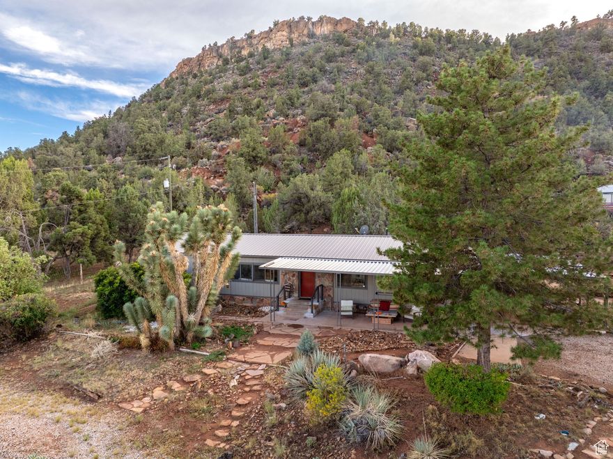 Discover this beautiful Apple Valley home where breathtaking views of Zion National Park and Gooseberry Mesa greet you right from the front door. Situated on a 1.18 corner acre lot in a peaceful cul-de-sac, this beautifully designed single-level home offers 4 spacious bedrooms, 2 bathrooms, living room and a cozy den with a wood-burning stove & sweeping views up Little Creek Mesa. The floor plan features abundant natural light with modern finishes & features. The patio with an unbeatable view and the expansive covered back patio connect you to the outdoors. The oversized 27-foot-deep garage provides room for vehicles, workshop, or storage, in addition to the 2-car carport and RV carport! Step outside to experience the wide-open desert skies and the unparalleled beauty of mountain landscapes.
