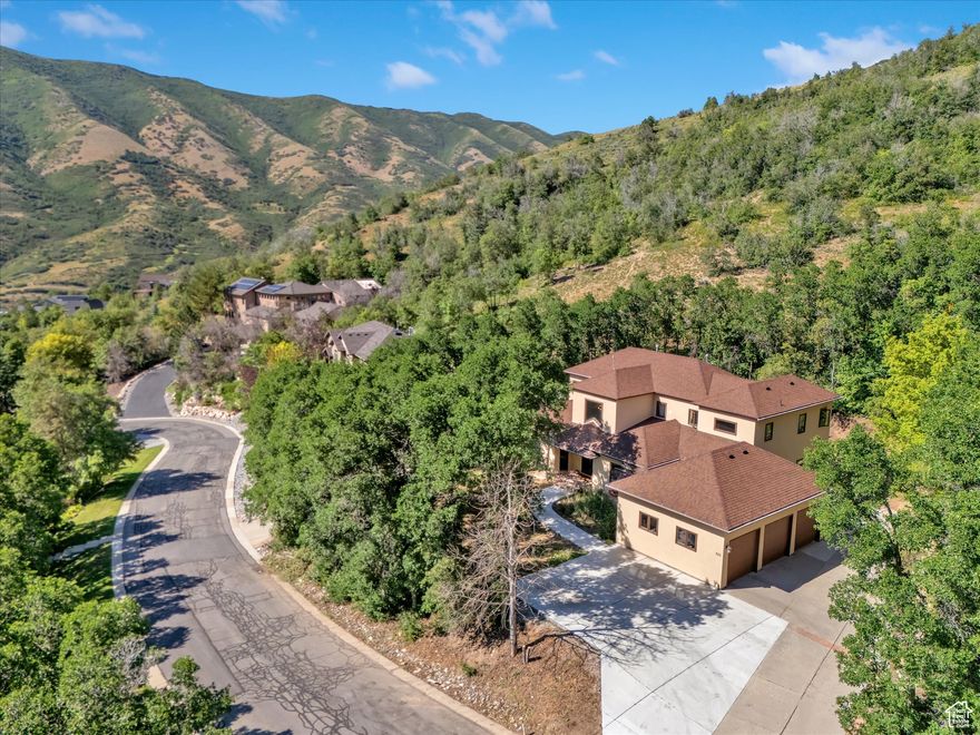 Nestled near the top of the gated community of Emigration Place, this spacious home invites you to enjoy the splendor of mountain living just minutes outside of Salt Lake City. With 5306 square feet, 5 bedrooms, 5 bathrooms, an office, multiple family rooms, and an elevator to provide ease of access to all three levels, there's room for every aspect of your lifestyle. The two-level entry invites you in with a sweeping stairway repurposed from a Salt Lake church and custom metal handrails which wrap around the glass and metal elevator. An oversized kitchen with two islands, a covered deck and formal and informal dining areas make entertaining a breeze. Upstairs another deck allows you to enjoy the beautiful sanctuary of Emigration Canyon just steps from your primary suite with fully renovated lux bathroom. A  junior suite completes the upper level. The basement features three more bedrooms, two full bathrooms, a theater room and additional family or game room. The 3-car garage with built in workbench is supplemented by additional parking for 3 more cars and the perfect spot for your camper or boat as you prepare to enjoy the outdoor recreation opportunities that surround you along the Wasatch front and back!