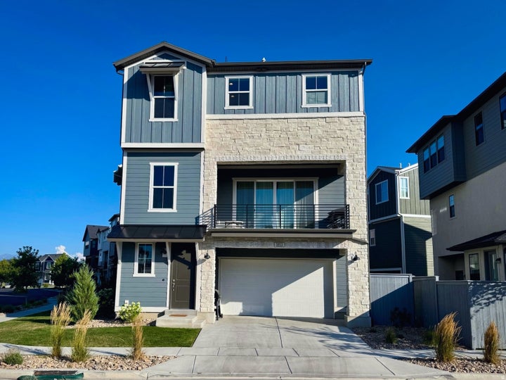 Modern two-story residence featuring a mixed-material exterior with stone and fiber cement siding, multi-pane windows…