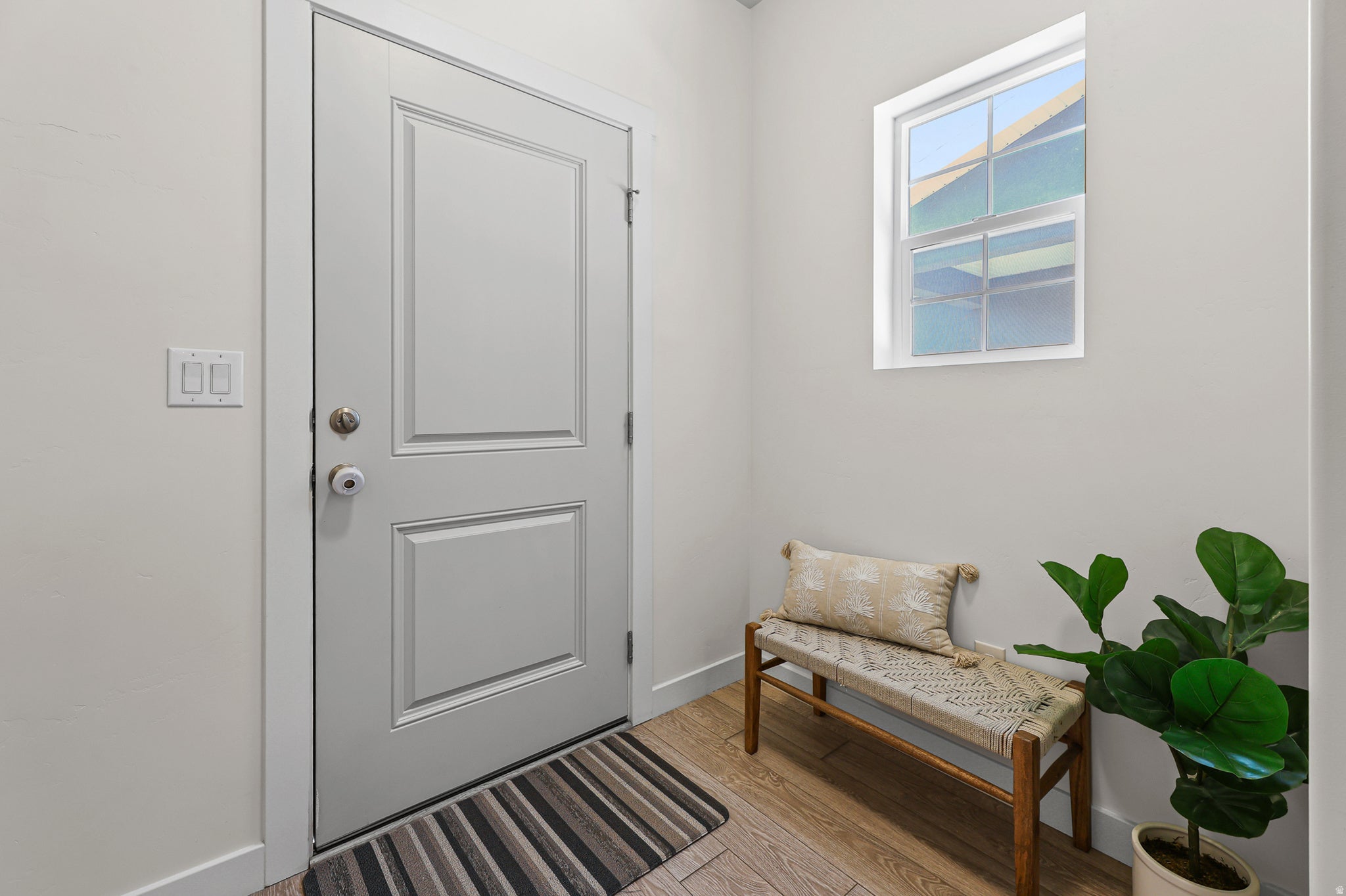 Entryway featuring a paneled door, wood-finish flooring, and a single pane window