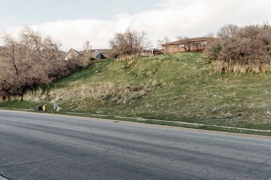 Perched high on Bountiful's coveted East Bench in the quiet Quailbrook neighborhood, this .29-acre homesite has sprawling views that encompass the valley below, the mountains beyond, and the glimmering Great Salt Lake in between. Despite the peaceful setting, you're just minutes to Bountiful's downtown amenities, or a quick commute to Salt Lake City and the airport. Bring your own creative vision to this lot, where the natural slope allows for a drive under garage design and elevated main level to capture panoramic views. Existing modern build plans are also available, specifically designed for this parcel by Urban Home, a design-build firm with a passion for minimal, compelling architecture. Utilities are stubbed and included plans have been stamped by engineers. The proposed build plans utilize simple materials-concrete, wood, glass and steel-with a minimal design that also values livability, function and comfort. Seemingly simple, it's supported by complex engineering and architectural creativity. Modern features include a floating fireplace, clerestory windows, movable shade panels for optimal light filtering and thermal gains, a wrap-around deck, an open floor plan and more. Intentionally designed with this lot's unique topography and natural light path in mind, the build orientation also maximizes the incredible sunset views and blends seamlessly into the hillside. Purchase the dream and then let Urban Home turn it into a reality....