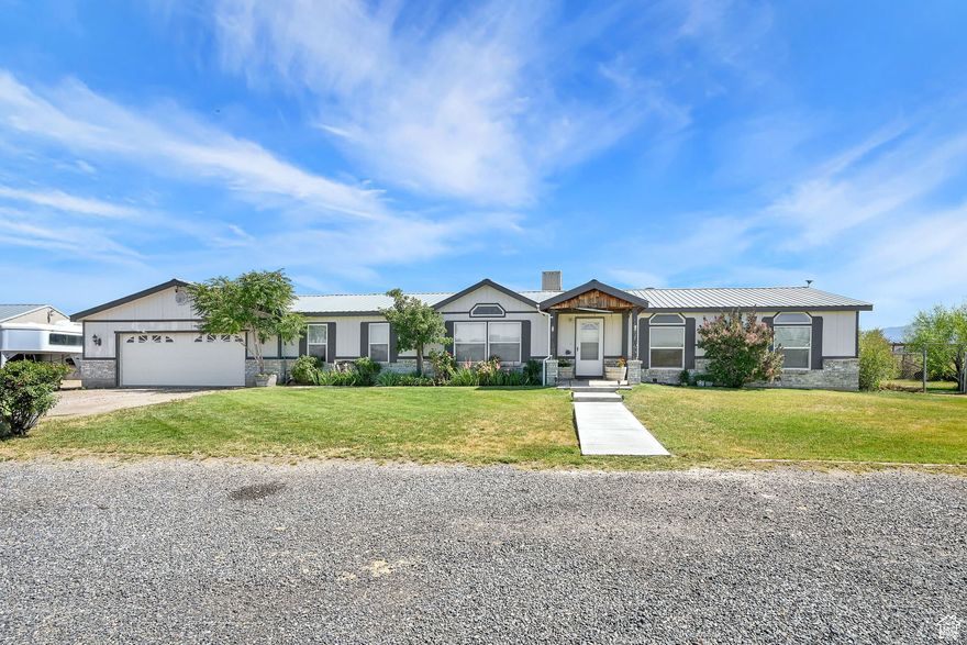 This 4-bedroom, 2-bath manufactured home sits on 5 acres and is a truly special piece of property in Davis County-perfect for anyone looking for space, functionality, and a place to enjoy country living. Whether you're into horses, hobby farming, or just want some room to breathe, this property checks all the boxes. Inside, the home is warm and welcoming with a cozy pellet-burning fireplace, durable laminate flooring, and a nice mix of carpet and tile throughout. The primary suite offers a walk-in closet, double vanity, and separate tub and shower. The layout is practical and well thought out, with a mudroom connecting the oversized two-car garage to the main living space-great for kicking off muddy boots and a separate laundry room with a sink. The kitchen comes move-in ready with the fridge and range included, and central AC keeps the home comfortable year-round. But the real draw is outside. You'll find a a great piece of horse property, with one barn, hay barn with a shed, wood corrals, a shed/tack-room with hot water, and a horse arena. The fenced yard is great for dogs, and there's plenty of space for trailers, RVs (with hookups), and more. The 30' x 18' covered patio gives you a shady place to relax or entertain, and a concrete slab under the crawlspace is a smart upgrade. Secondary water is close and expected to reach the front of the property in the future, making this an even more valuable long-term spot. If you've been dreaming of a place where you can live the country lifestyle without sacrificing comfort, this one's definitely worth a look.