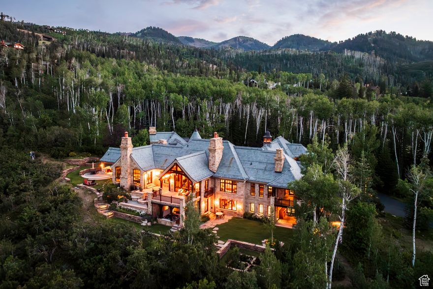 The Bastion, a master class in refined alpine living. This extraordinary ski-in/ski-out estate is located within the ultra-private, gated community of The Colony at White Pine Canyon. Set on 10+ private acres at a desirable lower elevation of 7,600 feet, sheltered from the wind and conveniently sited just two and a half minutes from the guarded entrance gate, this esteemed property offers direct, gravity-fed ski access to/from Harmony ski run, proximity to world-class mountain biking on Park City's Mid-Mountain Trail, sweeping panoramic views, and coveted year-round livability. This estate offers an exceptional sense of arrival. A wide, split-entry driveway with porte-cochre and spacious, heated auto court welcomes visitors. The property's placement within The Colony ensures rare peace and privacy; the home is set back an average of 1,500 feet from the main road, away from construction noise and traffic. The exterior is built for beauty and longevity, with low-maintenance, curated Nebraska and Oklahoma limestones, a Vermont green slate roof and mature, irrigated landscaping enhanced by subtle landscape lighting. This home is an architectural masterpiece, blending stately European elegance with rustic Western character. Rich finishes and materials sourced from around the world lend a sense of global sophistication, while Great Salt Lake-cured timbers, vaulted stone archways, and custom millwork ground the home's design in authentic mountain living. The interiors are richly layered with curated intention and artisan details speak to the home's refinement and comfort. Every detail of the interior design reflects thoughtful craftsmanship, from soaring timber-beamed ceilings and hand-laid stone archways to custom millwork and richly layered textures. This residence offers not only architectural excellence but also a rare harmony of comfort, beauty and character-ideal for those who appreciate artful living in a mountain setting.