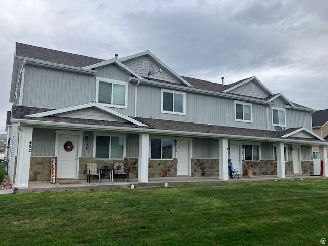 Multi-unit building featuring light gray vertical siding, stone veneer accents, white trim, and dark shingle roofing