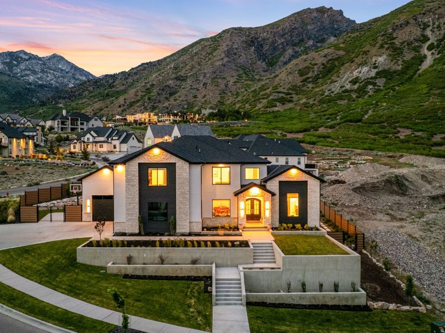Positioned in one of Alpine's most exclusive mountainside communities, this impressive custom home blends elevated architecture, designer finishes, and breathtaking views in every direction. From the moment you step inside, you're greeted by soaring ceilings, expansive windows, and a stunning custom staircase that anchors the home with timeless design and craftsmanship.  The chef's kitchen is a true showpiece, featuring Calacatta Vagli marble countertops and full-height backsplash, premium Monogram appliances, custom white oak cabinetry, and full cast brass hardware. Designer lighting and wide-plank engineered hardwood flooring elevate the home's warm, modern aesthetic throughout.  Designed for both everyday living and entertaining, the open-concept layout seamlessly connects the kitchen, dining, and living spaces while oversized sliding glass doors create effortless indoor/outdoor flow to the private backyard retreat. The resort-style pool features a dramatic waterfall spa, expansive patios, and unobstructed mountain views that feel truly unmatched.  The luxurious primary suite offers vaulted ceilings, oversized windows framing the mountainside, a spa-inspired bathroom with a freestanding soaking tub, and a custom walk-in closet complete with built-in laundry. Thoughtful details continue throughout the home, including a beautifully designed office featuring grass cloth wallpaper by Kelly Wearstler, custom built-ins, and curated designer finishes.  The basement was designed to impress, featuring an incredible entertainment space complete with a fully equipped theater room featuring 9.2 surround sound and an 8K Sony projector, game area, fitness space, kitchenette, and ample room for hosting family and friends.  Located near Lambert Park trails and Alpine's iconic poppy fields, this home offers a rare opportunity to own a thoughtfully designed luxury residence in one of Utah's most sought-after neighborhoods.