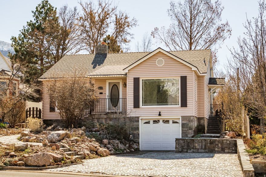 Perched high on Ogden's coveted East Bench and just steps from the trailhead, this walkable neighborhood setting is perfect for an owner who loves getting outside. Hardwood floors, a cozy fireplace, vinyl windows, and a solar system create an inviting and energy-efficient space. The updated kitchen features granite countertops, stainless steel appliances, and a breakfast bar that opens to the living room. Together with a large dining room, the layout is ideal for hosting friends or enjoying relaxed evenings at home. Large picture windows flood the space with natural light, while sliding glass doors lead to a covered back porch and a spacious backyard ready for summer gatherings, gardening, or simply unwinding after a hike. Handcrafted details add distinctive character, including a cobblestone double-width driveway, fully landscaped front garden, and beautiful stonework - all lovingly created by the longtime owner. The lower level offers a versatile family room, an additional bedroom ideal for guests or a home office, a brand-new three-piece bathroom, ample storage, and access to the attached garage.