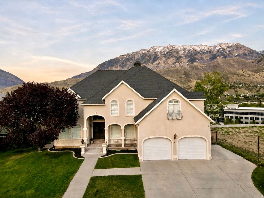 European-inspired luxury on Orem's east bench, just off Palisade Drive. Nearly 5,900 sq ft across three finished levels with panoramic views of Mt. Timpanogos, Cascade Peak, Y Mountain, and the Provo Rock Canyon Temple.  Grand marble foyer with curved staircase and hand-forged iron railing. Great room with soaring ceilings, stone fireplace, and curved glass wall framing the mountains. All-white kitchen with marble counters, wood-fired pizza oven, and curved island. Wraparound deck overlooking Provo Canyon and the Riverwoods.  Walk-out basement with separate entry, kitchen, and full bath - guest suite or rental ready.