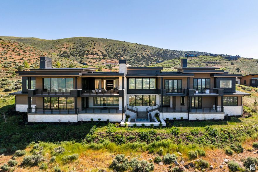 This luxury retreat at the pinnacle of desirable Red Ledges offers the opportunity to gather with friends and family in a breathtaking setting complemented by the year round recreational opportunities of this extraordinary lifestyle community. Designed by Kevin Price and Carol Levins and built by Red Ledges Construction, this stunning home provides a pervasive feeling of relaxation and expansiveness, bringing the outdoors in with multiple gathering areas highlighting sweeping views of Mt. Timpanogos, Deer Creek Reservoir, Deer Valley East and the Wasatch Mountains. From the moment you enter the front door, this impressive property is drenched in natural light, opening to a stunning foyer with glass sliders leading to a covered outdoor living area with kitchen, fireplace, and breathtaking views of the mountains in the distance. An open-concept layout featuring a gourmet kitchen defined by carefully selected stone and elegant lighting includes an adjacent dining area with a temperature controlled wine wall. A spacious, luxurious primary suite offers the added amenities of a fireplace, beverage bar and private terrace, with two separate, oversized closets and an indulgent, spa-like bathroom with soaking tub and stunning views. Downstairs, two guest bedrooms with private decks and a bunk room are steps away from a second living and entertainment area with a dry sauna and walk-out patio with steps leading down to a private terrace with an 8 person hot tub and oversizedfirepit overlooking the expansive valley and mountain vista in the distance. The epitome of luxury, this layout boasts an additional 1,400 square feet of outdoor living areas, an ideal retreat for day to day enjoyment and entertaining friends and family after golf, tennis, swimming, horse-back riding, biking, or skiing. Red Ledges is a year round lifestyle community with numerous daily ski shuttles to/from Deer Valley Resort and East Village. Additionally,there is a Golf Membership available for this home, and the adjacent lot is available for purchase.