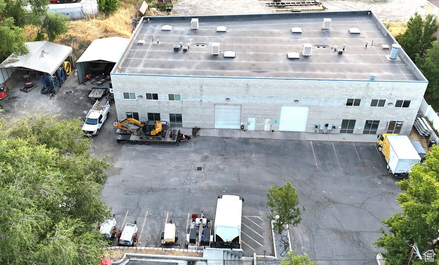 Two minutest to I-15. 9000 SF warehouse with 5000 SF of office space AND 0.30  acre adjacent overflow parking with two 30' X 28' covered parking. Two 14' X 12' garage doors with 21' ceiling height in warehouse. The overflow yard aera is lease for $6,000 a year with 16 years remaining. Warehouse space is in the center of the buildings with the office space on the outer edges. All office space is newer within the last couple of years. Gas powered back up Generac generator recently installed 2024. Warehouse is heated and cooled. Plenty of parking. Warehouse power: 200 Amp 277 Volt // 400 Volt 3-Phase Power. Current configuration is 15 individual office suites, two large open office spaces used as call centers, one break room, four bathrooms, two data center utility rooms. Fiber connected for communication. Office furniture included. This listing is for 4694 & 4696 S. 200  W. The building envelope is 0.250, the common site is 0.64 acres, therefore the allocated total lot size of the site is 0.68 acres. Additional 5550 SF building in adjoining/connected lot also available. See MLS # 2101743.