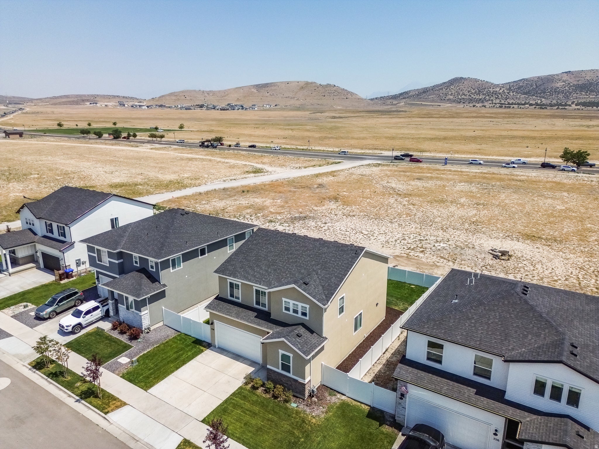 Aerial perspective showcasing multiple properties, residential street, and distant natural landscape
