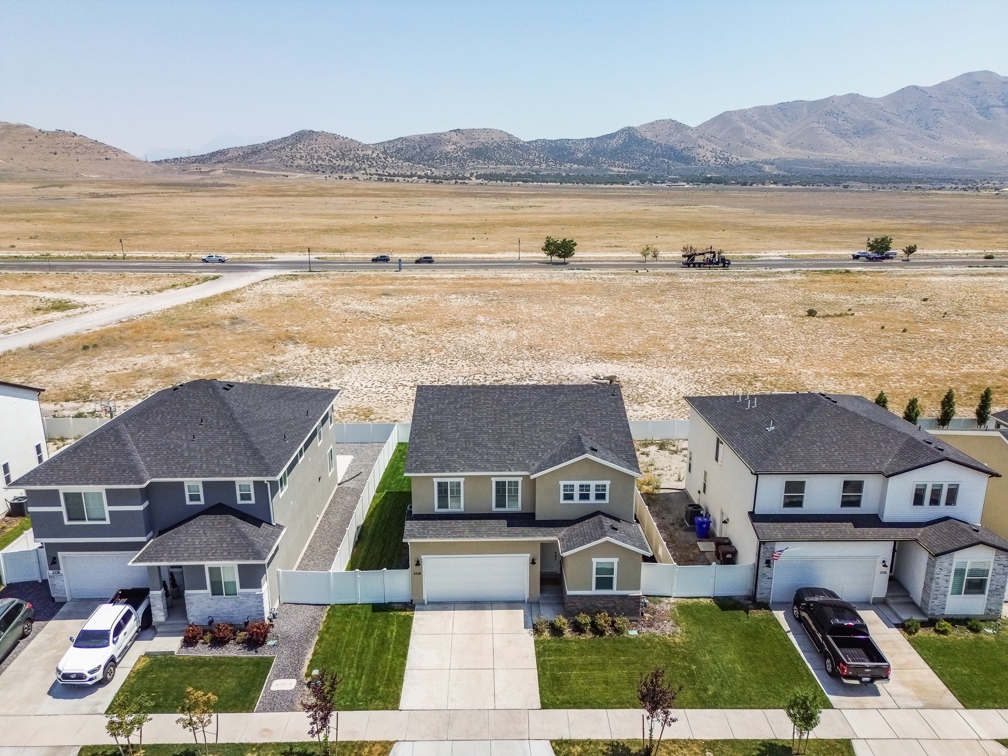 Modern two-story residence with a two-car garage, dark shingle roof, and a fully fenced yard