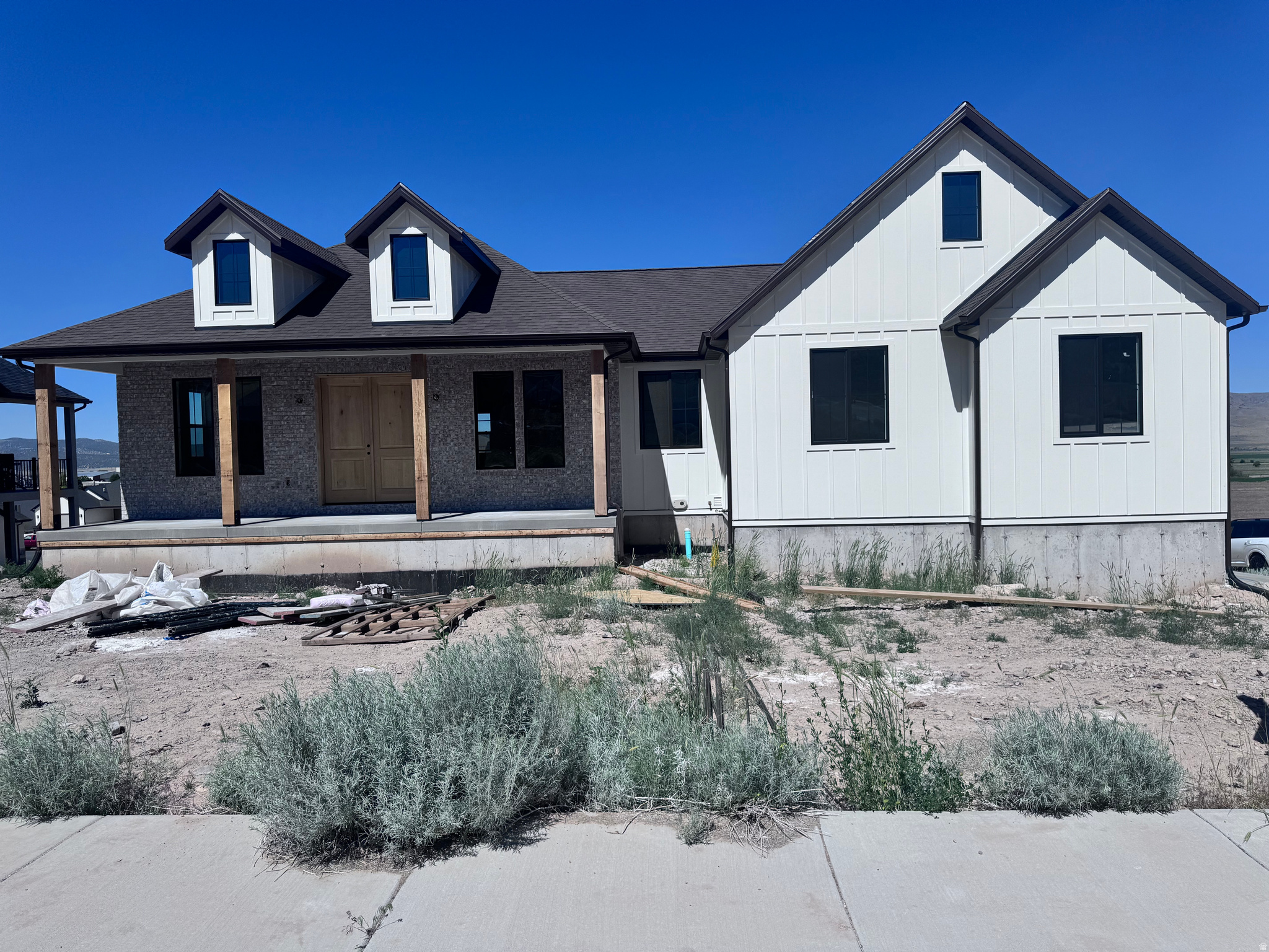 Contemporary home exterior featuring a covered porch with natural wood posts, a light-colored double entry door, and dark-framed windows