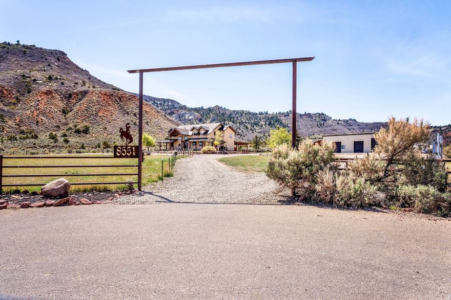Tucked into the heart of Dry Fork Canyon, this remarkable 8-acre estate offers more than a home-it delivers a lifestyle surrounded by some of Vernal's most iconic scenery. Towering Navajo sandstone cliffs create a dramatic backdrop, while nearby access to McConkie Ranch Petroglyphs, the Flume and Narrow trailheads, Red Cloud Loop, Flaming Gorge, Red Fleet Reservoir & Ashley Gorge via Ferrata puts outdoor adventure close by. A covered wrap-around porch welcomes you into a thoughtfully designed residence where craftsmanship and comfort meet. Inside, the great room makes an unforgettable first impression with soaring 24-foot tongue-and-groove vaulted ceilings, expansive wood-framed windows, and a striking floor-to-ceiling stone fireplace, complemented by a Blaze King wood catalytic stove. Natural light and panoramic canyon views fill the space, creating a true sense of mountain elegance. The kitchen serves as the heart of the home, featuring granite and quartz countertops, custom alder cabinetry with built-in details, a gas range, and a new updated refrigerator. Whether gathered at the breakfast bar or seated in the charming circular dining nook, every space is designed to take in the surrounding views. The main-level primary suite offers a peaceful retreat, complete with a spa-inspired bathroom featuring a freestanding soaking tub, walk-in shower, and walk-in closet. With four bedrooms and two-and-a-half bathrooms, the home balances comfortable private spaces with inviting areas for entertaining. Designed with both function and versatility in mind, the property is fully equipped for animals and hobbies alike. Much of the acreage is pipe-fenced, with established pasture on the front and south side, and a fully fenced back area that includes a 20' x 24' lean-to. The impressive 3,500 sq. ft. red iron shop with attached lean-to provides exceptional workspace, featuring five bay doors, 200-amp separate service, commercial-grade wiring, a 50-amp RV hookup, and dedicated areas for storage, projects, and even a custom sauna. Outdoor living is just as exceptional, with a stamped patio, pergola, and custom rock firepit area perfect for enjoying peaceful canyon evenings. Additional amenities include a high-fenced garden, chicken coop with run, covered hay storage, multiple water hydrants, and ample storage throughout. The property is also supported by 1,000-gallon and 500-gallon propane tanks for added convenience. This is a rare opportunity to own a private canyon retreat that seamlessly blends refined living with the rugged beauty of the surrounding landscape. Buyer to verify all information, including square footage.