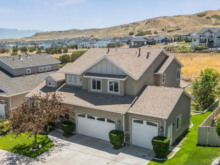 Welcome to Juniper Point! This beautifully maintained home offers breathtaking views of the Wasatch Mountains and is located just steps from the community clubhouse, pool, trails, and sports courts. The main level features soaring ceilings, hardwood floors, and a versatile front room perfect for an office or sitting area. The open-concept kitchen, dining, and family room are ideal for entertaining, complete with a cozy fireplace and access to a covered deck with no rear neighbors. The spacious main-floor primary suite includes dual sinks, a walk-in shower, an oversized soaking tub, and a walk-in closet. Upstairs, you'll find three large bedrooms and a full bathroom. The daylight walkout basement is fully finished with 9' ceilings, a second full kitchen, three additional bedrooms, and direct access to a private, landscaped backyard-perfect for multi-generational living or rental income. Additional features include a brand-new roof with a warranty, a three-car garage-third car garage has a 10' tall door, proximity to Providence Hall Charter School, and easy access to Mountain View Village, shopping, dining, and SLC commuter routes.