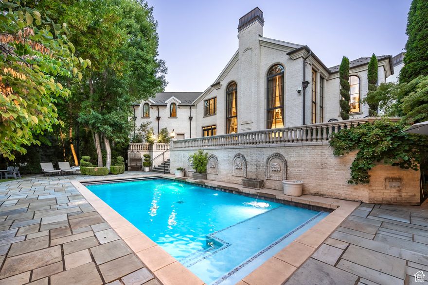 Thisextraordinary custom estate is nestled within the exclusive gated enclave off Holladay's famed Walker Lane. Set on spectacular grounds with mature trees, manicured gardens, and a resort-style pool, this residence blends timeless European elegance with thoughtful modern amenities.The grand foyer sets the stage with marble floors and chandeliers imported from France. Throughout the home, exquisite millwork, hand-carved fireplaces, and bespoke light fixtures showcase unrivaled craftsmanship. An executive office features rich wood paneling, a gas fireplace, and a rolling library ladder leading to a lofted gallery, perfect for art, books, or quiet reflection. The formal dining room, anchored by a fireplace and expansive picture windows, seamlessly connects to a butler's pantry and the chef's kitchen, which boasts an oversized island, custom cabinetry, dual dishwashers, two sinks, and a full suite of luxury appliances. The kitchen opens to a soaring great room with floor-to-ceiling windows and casual dining spaces, ideal for entertaining or everyday living.The main level offers both formal and informal gathering areas, charming play spaces, generous storage, and a spacious five-car garage. The primary suite is a private retreat, complete with a lounge/office, gas fireplace, expansive his-and-hers closets, and separate spa-inspired bathrooms with soaking tubs, marble showers, and dressing vanities.Upstairs, three large en-suite bedrooms, a loft, a second laundry, a whimsical French-inspired playroom, and a vaulted theater create a welcoming and versatile layout.Outdoors, the estate transforms into a private resort setting with a pool, hot tub, outdoor kitchen, stone patios, and a two-bedroom, two-bath pool house with full kitchen and living room, ideal for extended guests. Across the stream, a storybook pavilion on the edge of the water invites moments of gathering, play, and celebration.Located in one of Utah's most coveted neighborhoods, this estate offers unmatched privacy while being minutes from downtown, world-class skiing, shopping, dining, and outdoor recreation. Every detail has been meticulously curated, making this one of Utah's most remarkable offerings.