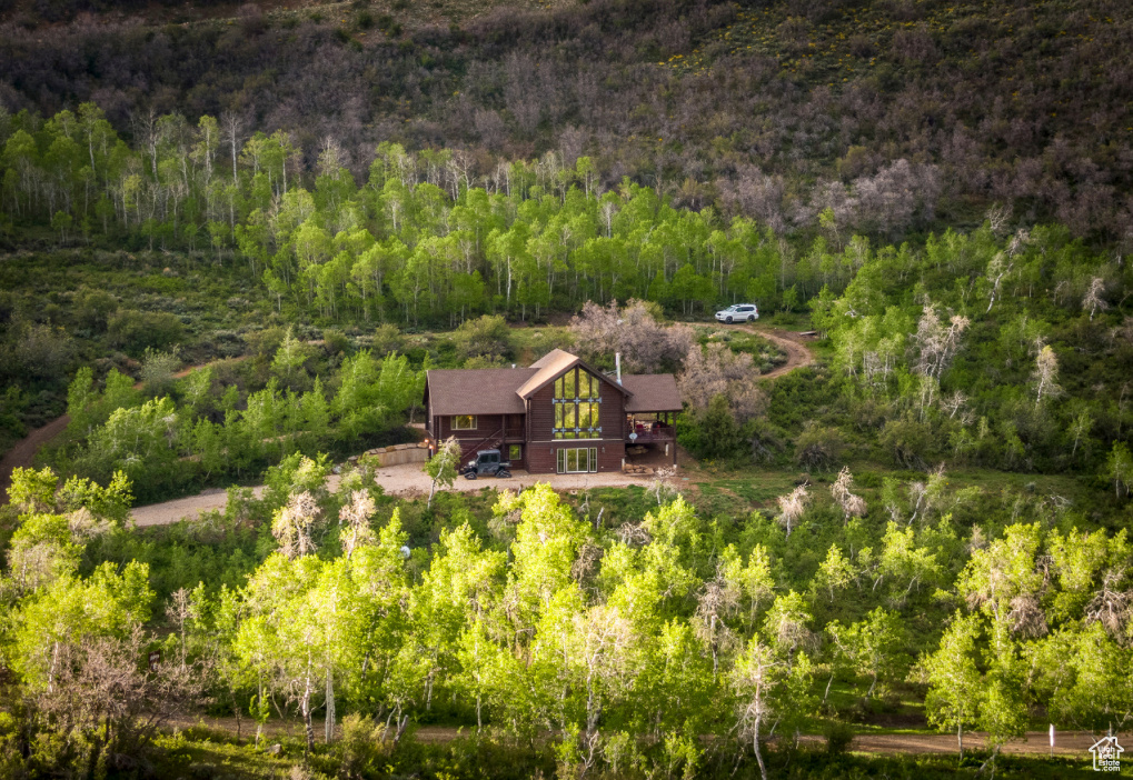 Located on 5 acres in the gated community of Canyon Rim Ranches, this turnkey mountain cabin offers stunning views of the Wasatch Mountains, Weber Canyon, and Uinta range. Surrounded by aspens and wildlife, the home provides direct access to fishing, hiking, ATV riding, skiing, and more with Smith & Morehouse Reservoir and the Weber River just minutes away. The cabin features vaulted ceilings, floor-to-ceiling windows, a large covered deck, and an open floorplan ideal for entertaining. It includes two bedrooms on the main floor, a lofted master suite, and a finished walk-out basement with family room and fireplace. Quality finishes include granite counters, stainless steel appliances, designer shades, and updated baths. Built for both comfort and peace of mind, the property offers a 22k-watt generator, 3,500-gallon water tank, security system, and oversized garage plus storage shed. Extras include two ATVs and optional Kawasaki Mule with snow tracks for year-round access.