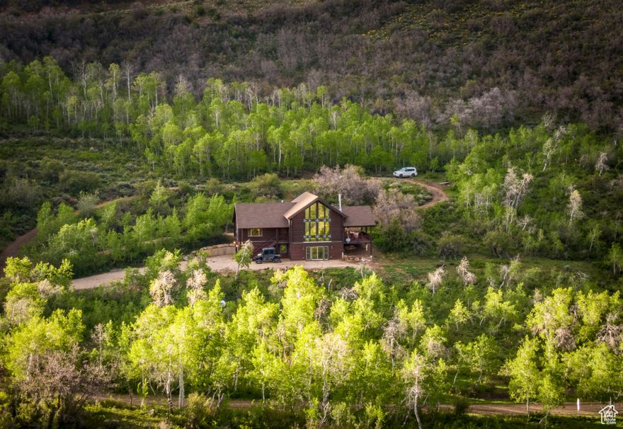 Located on 5 acres in the gated community of Canyon Rim Ranches, this turnkey mountain cabin offers stunning views of the Wasatch Mountains, Weber Canyon, and Uinta range. Surrounded by aspens and wildlife, the home provides direct access to fishing, hiking, ATV riding, skiing, and more with Smith & Morehouse Reservoir and the Weber River just minutes away. The cabin features vaulted ceilings, floor-to-ceiling windows, a large covered deck, and an open floorplan ideal for entertaining. It includes two bedrooms on the main floor, a lofted master suite, and a finished walk-out basement with family room and fireplace. Quality finishes include granite counters, stainless steel appliances, designer shades, and updated baths. Built for both comfort and peace of mind, the property offers a 22k-watt generator, 3,500-gallon water tank, security system, and oversized garage plus storage shed. Extras include two ATVs and optional Kawasaki Mule with snow tracks for year-round access.