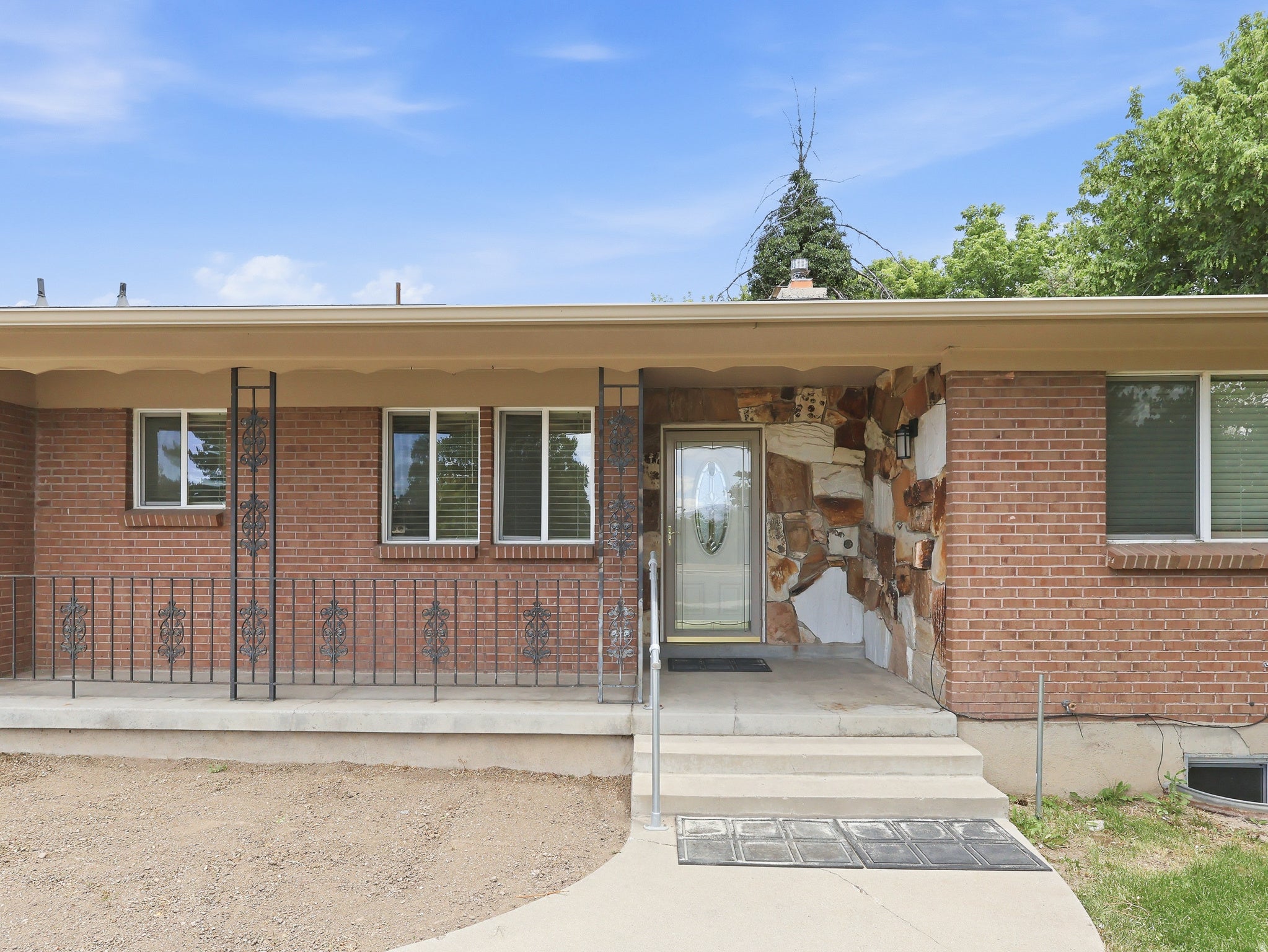 Brick exterior featuring a covered porch with decorative wrought iron railing