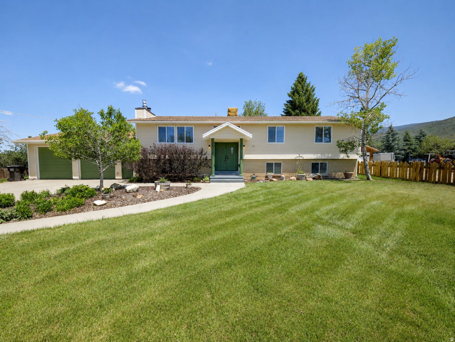 Light-colored exterior with a green front door and garage doors