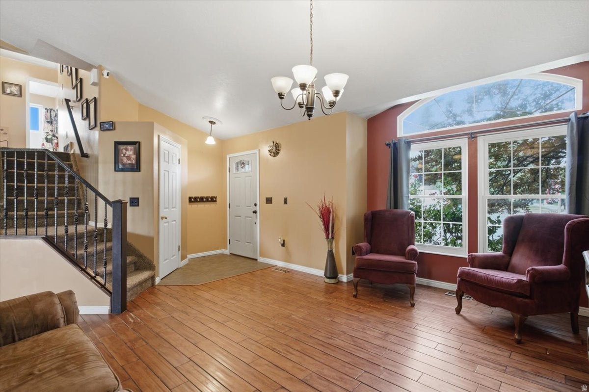 Hardwood-finish flooring, staircase with metal balusters, arched transom window, white paneled doors, and a chandelier lighting fixture