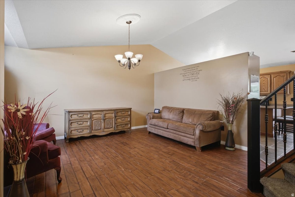 Vaulted ceiling with a flush-mount chandelier, wood-finish flooring, and a half-wall partition