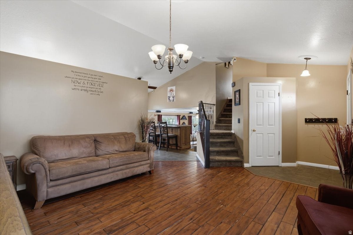 Varnished wood-finish flooring, vaulted ceiling, multi-level design, paneled interior door, and built-in staircase