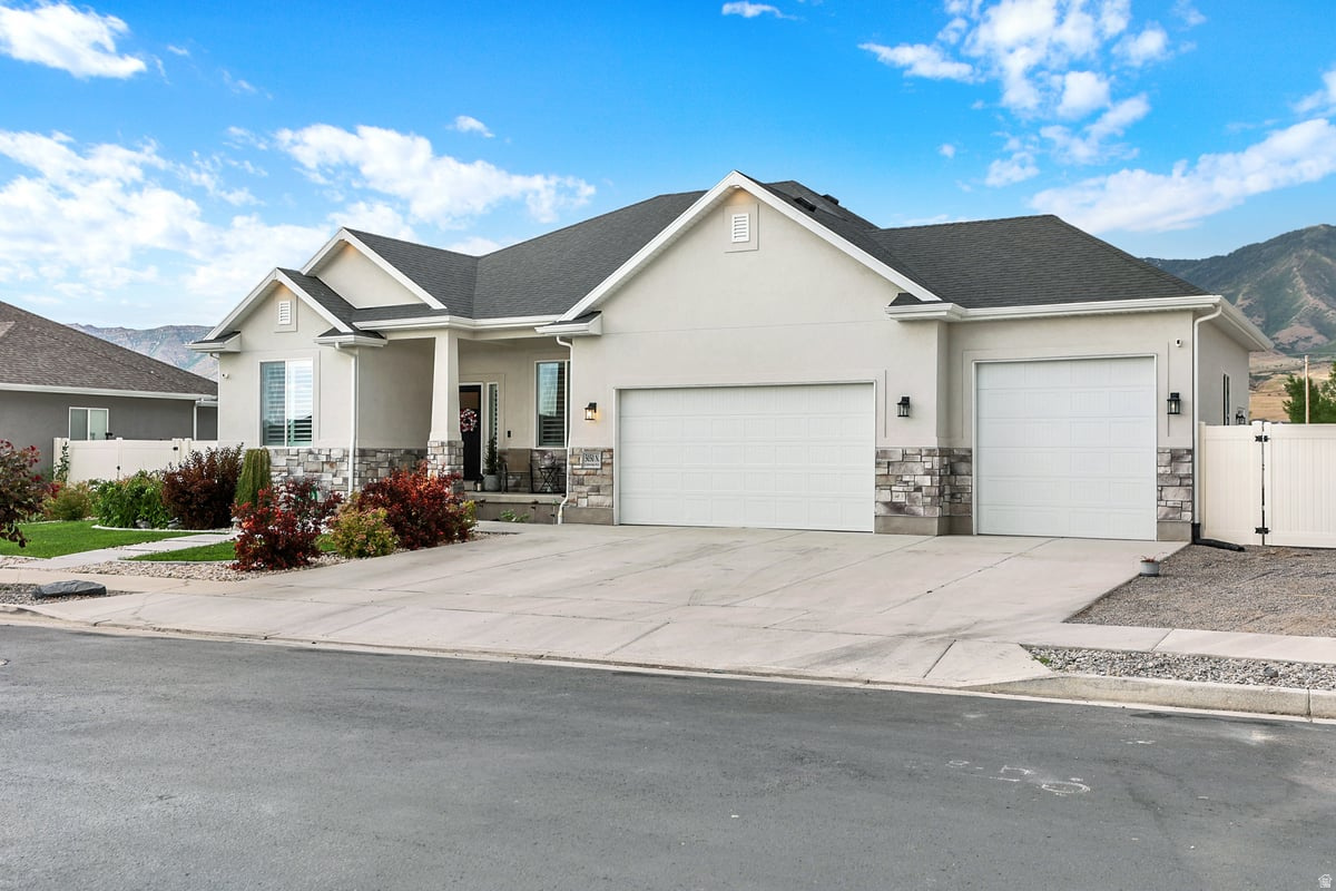Contemporary stucco exterior with stone accents, featuring a covered porch entry and a two-car garage