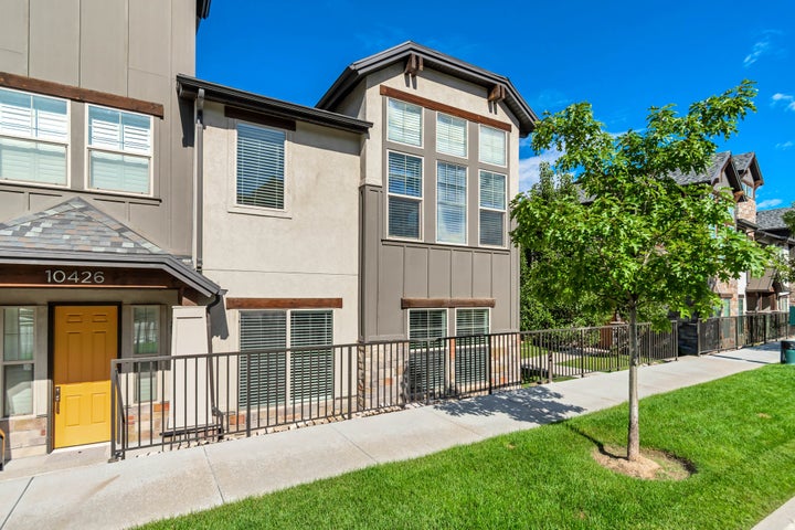 Contemporary facade with stucco and wood-look siding, multi-pane windows with blinds, a prominent yellow front door…