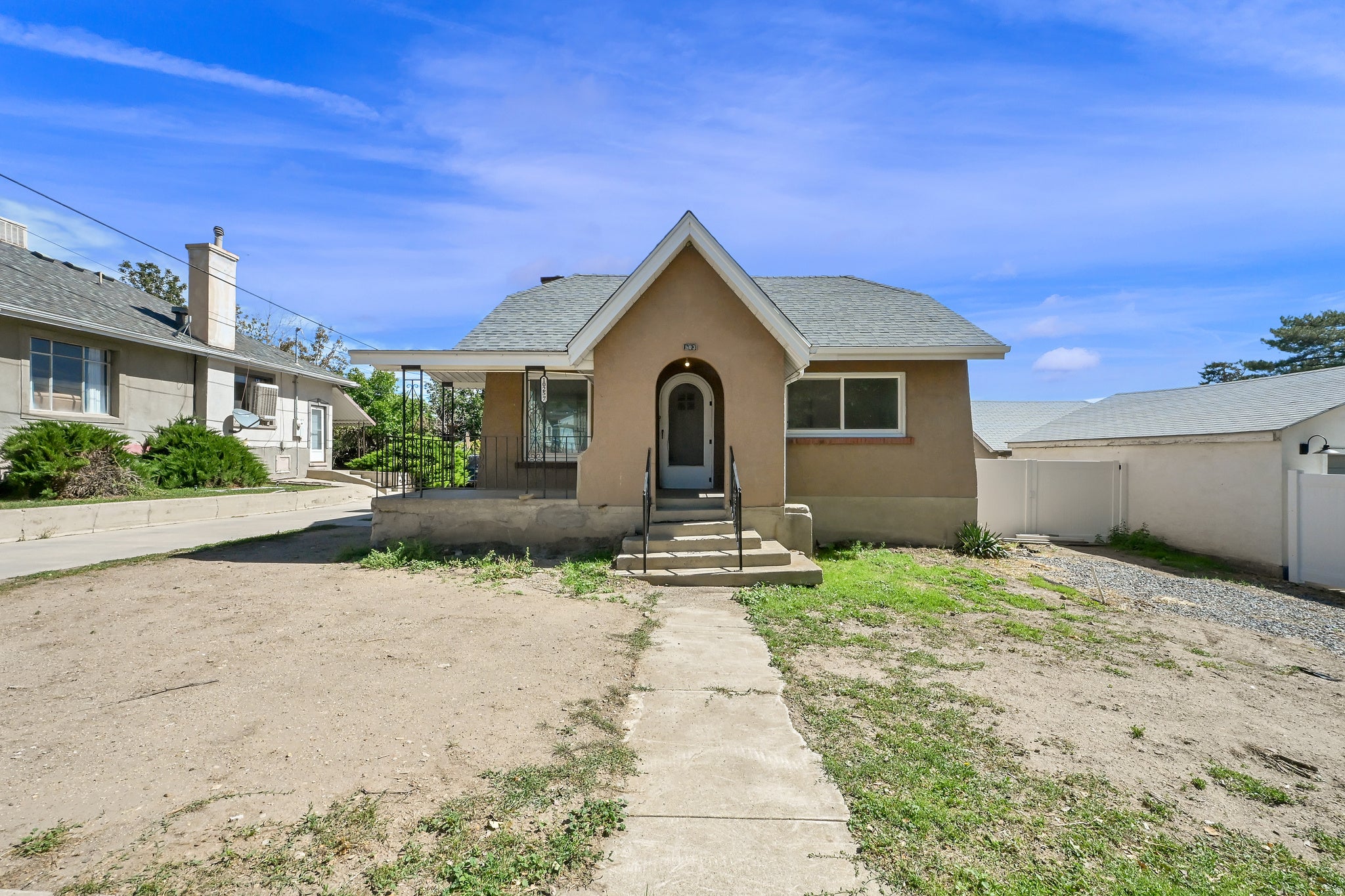 Stucco exterior with a peaked entry, covered porch, and asphalt shingle roof