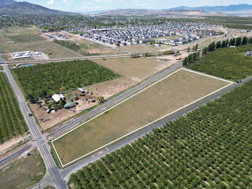 Spanning 5.76 acres, this residential agricultural property provides a prime opportunity for those in search of productive land surrounded by natural beauty. The parcel comes with 11.2 water shares and is outfitted with pressurized irrigation, making it ideal for farming operations or maintaining livestock. Fully enclosed and presently used for cattle grazing, the property is both efficient and adaptable to a variety of uses. Enjoy sweeping mountain and valley views, all while being situated next to established orchards and a newer residential development-offering a unique combination of quiet country living and convenient proximity to growth.