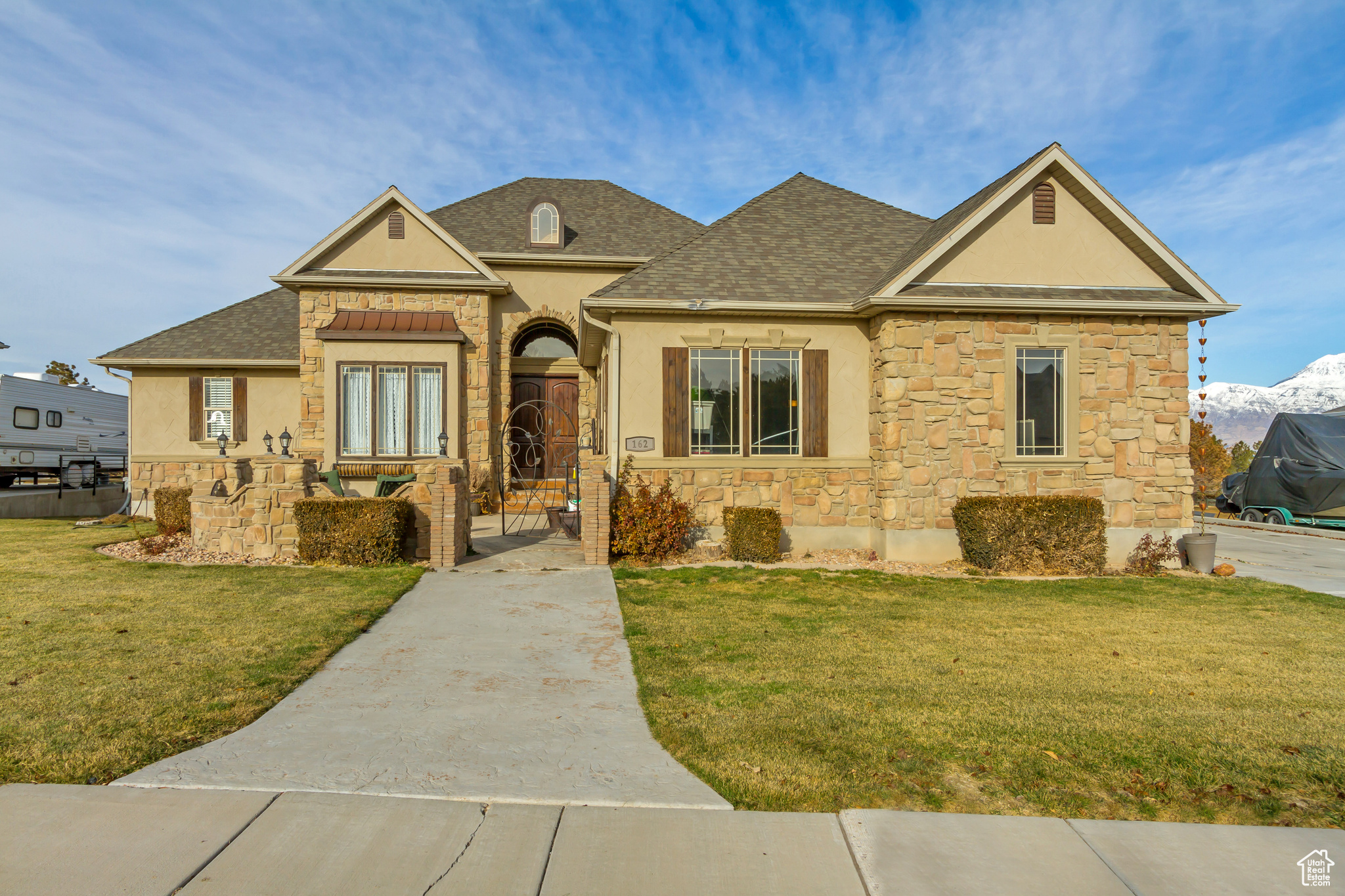 Welcome home!! Pelican Bay rustic, Tuscan-style estate with incredible lake and mountain views! Through the stone alcove, solid wood double doors open inside to tumbled travertine and hand-scraped wood floors. Beyond the foyer, the formal living and dining rooms have a wall of monumental windows to take full advantage of the dazzling view! No detail was overlooked in the kitchen with the wood inlay in the tile floors, and storage and display areas in the cabinetry. Kitchen sink with a window, and a separate copper prep sink in the island! The great room walks out to large covered deck that looks across the open backyard to a park with evergreens, the lake and the mountains just beyond! This home is just a short distance to the boat harbor. Evenings bring out the twinkling city lights that shimmer over the lake. Stunning! The master bedroom has its own entrance to the covered deck. The master also has a master bath with two vanities, water closet, separate tub, shower with extra tall ceiling and rain showerhead, and a large walk-in closet. The main floor of this home also has a second bedroom with a full bathroom, a study/office with a closet, the laundry room, and a guest's half bathroom. The bathrooms have heated floors! Single level living is possible here! Need more space? The basement is finished with three total bedrooms, one of them large enough to be a downstairs master with a fireplace, a full bathroom, a large living/gaming area, plentiful storage rooms, and a walkout to the backyard. New furnace and A/C in 2019. Ample parking available with the three car garage and additional space for an RV or boat. Come check out this Beauty!!!