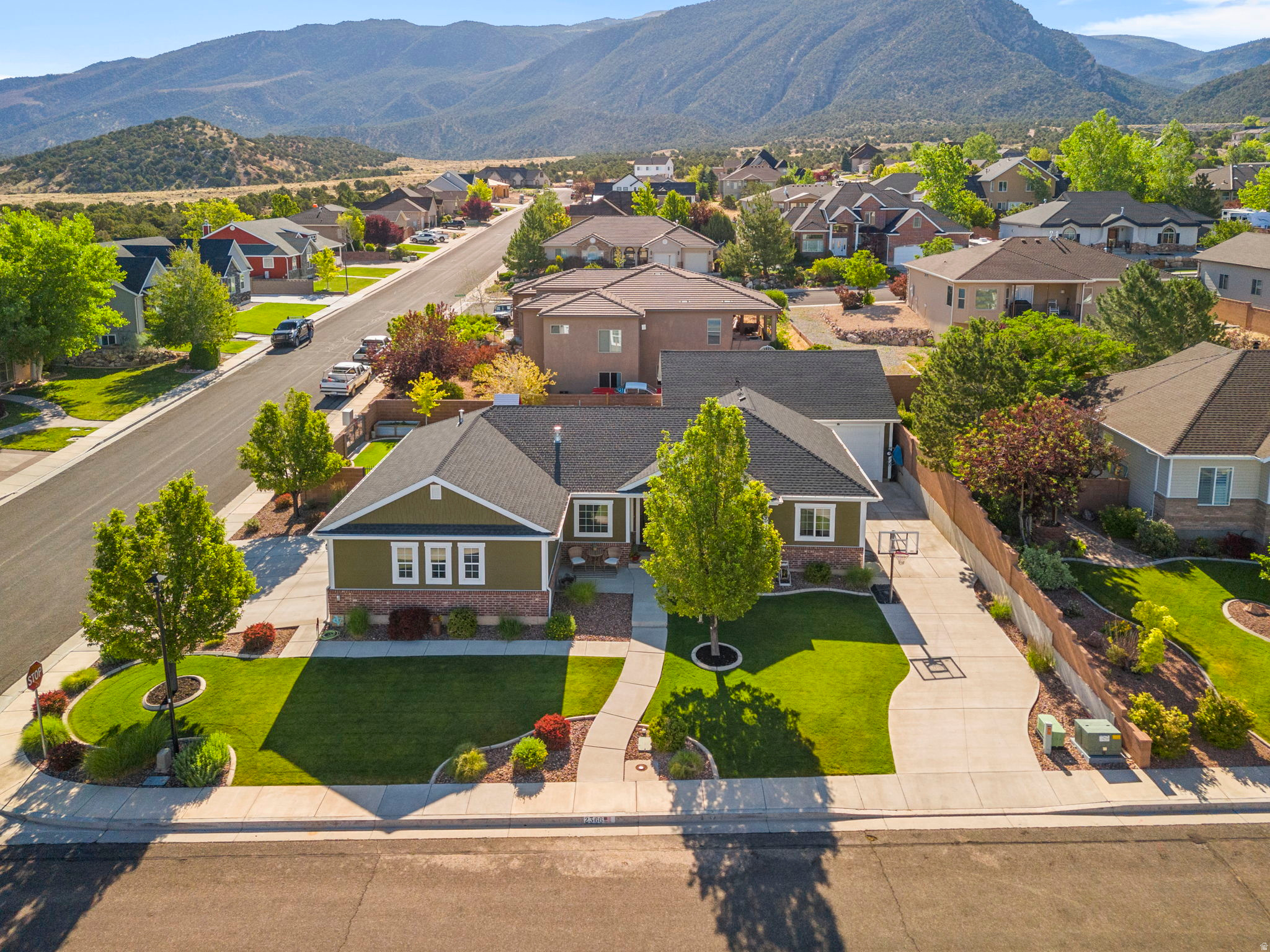 Aerial perspective of a residence featuring a dark shingle roof and a green siding and brick facade