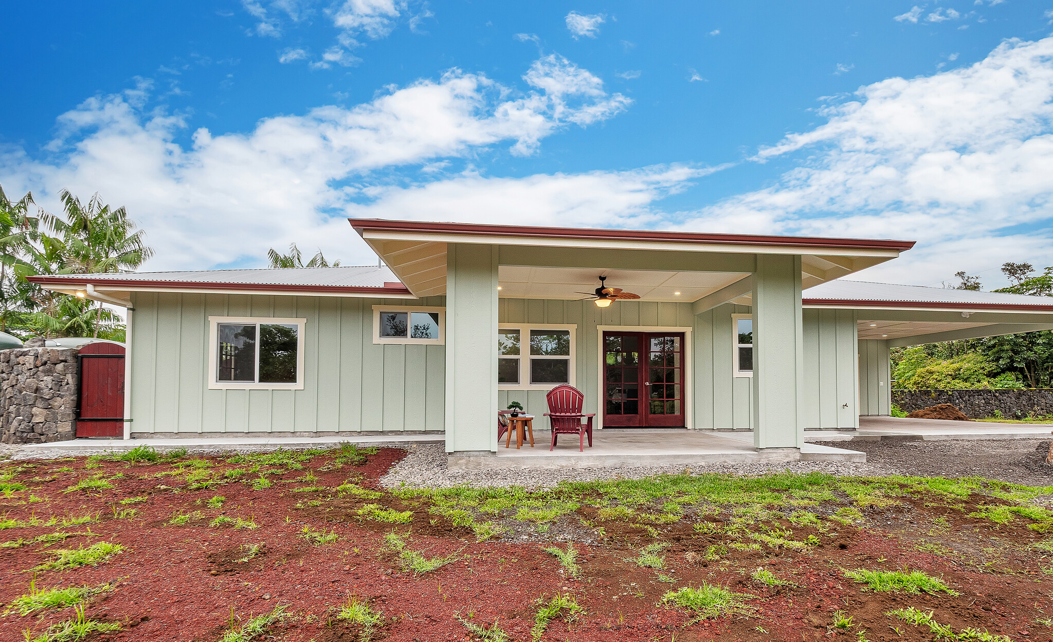 View of the front exterior highlighting the beautiful rock wall and tropical landscaping. Perfectly situated to enjoy the cool ocean breezes of Hawaiian Paradise Park.