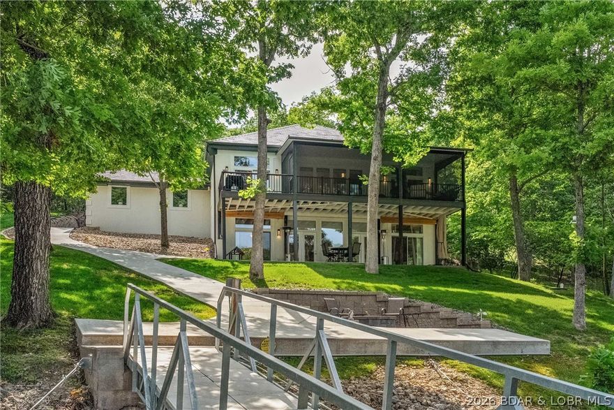 Tucked away in the prestigious Villages at Shawnee Bend, this updated lakefront home delivers the lifestyle buyers want without the maintenance & expense of a massive estate. Situated on 2 lots with 190 ft of protected shoreline, this property offers privacy, calm water, & a setting that is hard to match at this price point in this community. With nearly 3,000 sq ft, the home features 3 spacious suites plus an office large enough to function as a 4th sleeping area. The main level primary suite is a retreat with a spa-inspired bath, while the lower level suites offer excellent space & access to lakeside patio. Extensive recent improvements  include new paint, a DaVinci roof, flooring, fixtures, appliances, vanity tops, a gorgeous fireplace with herringbone tile surround, screened porch addition, new driveway, golf cart path, firepit area, and a premium custom concrete dock complete with a 12x32 slip, shallow water boat lift, & swim platform. The lakeside setting is exceptional, private yet still offering water depth suitable for larger boats. Homes in The Villages at Shawnee Bend rarely offer this combination to enjoy luxury lake living without the price of the mega-estates nearby.